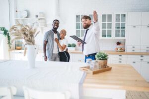 Buyer and real estate agent reviewing a property listing, contract papers, and a map at a kitchen table.