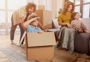 A homeowner arranges neutral furniture and clears clutter in a bright living room before a showing.